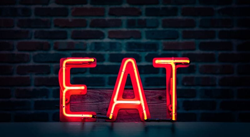 Neon sign illuminating the letters EAT, symbolizing the SEO principles of Expertise, Authority, and Trustworthiness.